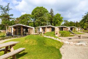 een rij houten cabana's met banken en een speeltuin bij TopParken – Bospark Ede in Ede
