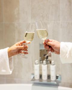dos personas sosteniendo copas de vino blanco en el baño en RÌGH Properties - Luxury West End Artisan Apartment, en Edimburgo