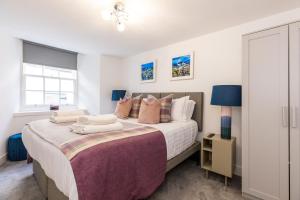 una camera da letto con un grande letto con cuscini di RÌGH Properties - Luxury West End Artisan Apartment a Edimburgo