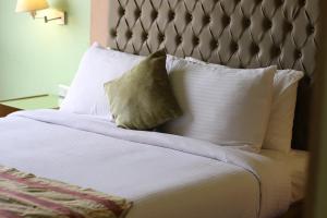 a bed with white pillows and a gray headboard at Santana Hotel Cairo in Cairo