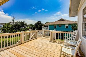 a wooden deck with two chairs and a blue house at The Happy Place in Edisto Island