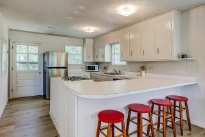 a kitchen with white cabinets and red bar stools at The Happy Place in Edisto Island