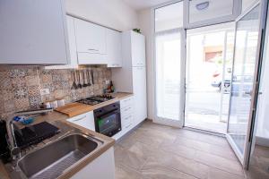 uma cozinha com armários brancos, um lavatório e uma janela em Casa Elda em Marina di Ragusa