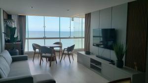 un salon avec une télévision, une table et des chaises dans l'établissement Maravilhoso frente mar, à Balneário Camboriú