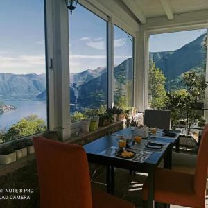 a dining room with a table and views of the mountains at Essentia Guest House in Faggeto Lario 