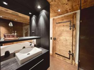 ein Badezimmer mit einem Waschbecken und einer Holztür in der Unterkunft Reseda 222 in Crans-Montana