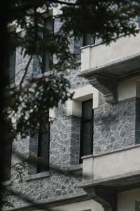 un edificio de piedra con ventanas y un árbol en el primer plano en MANNA en Valtessiniko 