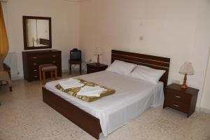 a bedroom with a bed with white sheets and a mirror at Odysseas & Eleni Hotel Apartments in Polis Chrysochous