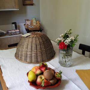 a table with a bowl of fruit and a vase of flowers at B&B Marana 14 Casa di Campagna in Bologna