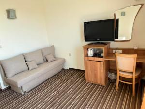 ein Wohnzimmer mit einem Sofa und einem Flachbild-TV in der Unterkunft Hotel Lalov Egrek in Lozenets