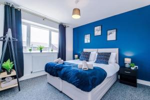 een blauwe slaapkamer met een groot bed met blauwe muren bij Penny Bridge Home From Home in Saint Helens