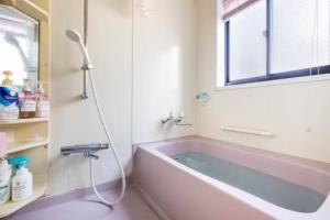 baño con bañera rosa y ventana en Noriko's Home - Vacation STAY 13624 en Kawasaki