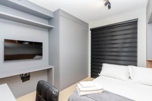 1 dormitorio con 1 cama y TV de pantalla plana en Studio incrível no condomínio clube sky Batel soho, en Curitiba