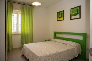 1 dormitorio con cama verde y cortinas verdes en RizzoRelax B&b io mammata e tu en Capilungo