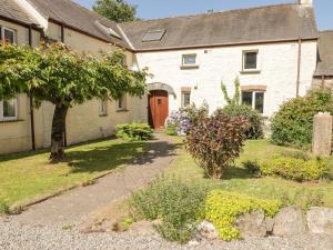 a white house with a red door and a yard at 2 Yr Hen Felin in Haverfordwest
