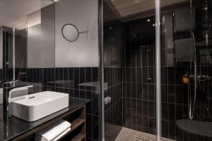 a bathroom with a sink and a glass shower at Hotel ROMY by AMANO in Berlin