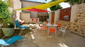 un patio con mesa, sillas y sombrilla amarilla en Gîte Chez Les Brocs, en Canet d'Aude