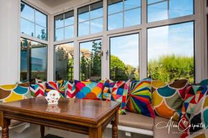 un sofá con almohadas coloridas sentado frente a una ventana en Beachside period family home. 5 BR spacious, comfortable., en Dymchurch