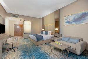 um quarto de hotel com uma cama, um sofá e uma televisão em Seven Gardens Hotel em Riade