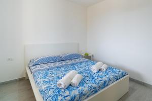 Una cama con sábanas azules y blancas y toallas. en Il Paguro, en Pachino
