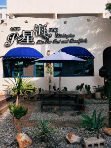 a patio with a bench and umbrellas in front of a building at Qixingtan Xinghai B&B in Dahan