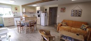 eine Küche und ein Wohnzimmer mit einem Sofa und einem Tisch in der Unterkunft Gîte Des Huttes in Bain-de-Bretagne