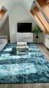 sala de estar con alfombra azul y TV en FeWo-Julius am Weser-Sandstrand, en Berne