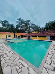 a swimming pool in front of a house with blue water at Hotel Boavista in Miguel Pereira