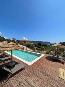 a swimming pool with chairs and umbrellas on a wooden deck at BnB Il Grecale in Lacona