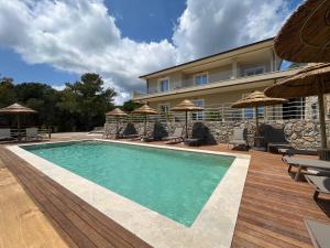 a swimming pool with chairs and umbrellas next to a building at BnB Il Grecale in Lacona