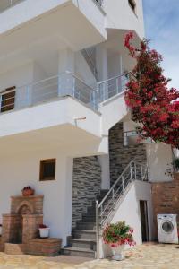 een wit gebouw met een trap met rode bloemen bij Vila Genci in Ksamil