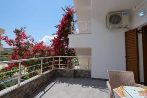 een balkon van een huis met rode bloemen bij Vila Genci in Ksamil