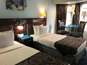 カイロにあるSantana Hotel Cairoのベッド2台、テーブルと椅子が備わるホテルルームです。