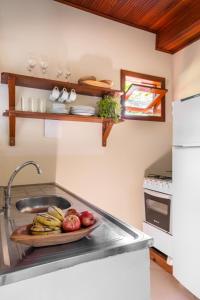 a kitchen with a sink and a plate of fruit at Aldeia dos Corais - Taipu de Fora in Barra Grande