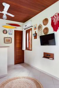 een woonkamer met een flatscreen-tv aan de muur bij Aldeia dos Corais - Taipu de Fora in Barra Grande