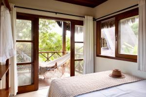 - une chambre avec un lit et des portes coulissantes en verre dans l'établissement Aldeia dos Corais - Taipu de Fora, à Barra Grande