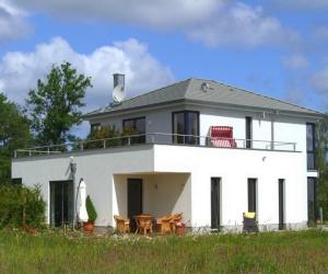 a white house with chairs and tables in front of it at Villa im Grünen excl Privatsphäre in Wittenbeck