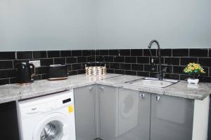 eine Küchentheke mit einer Waschmaschine und einem Waschbecken in der Unterkunft All-Inclusive Living: Modern Studio in Liverpool