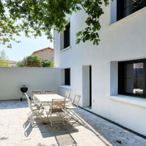 a patio with a table and chairs in front of a white building at Grande Plage in Saint-Georges-de-Didonne