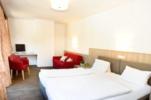 a hotel room with two beds and a red chair at Gasthaus Bacher in Sankt Johann im Pongau