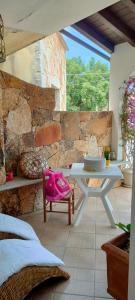 uma mesa branca e uma cadeira num quarto com uma parede de pedra em Villa Alberto em Olbia