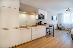 eine Küche mit weißen Schränken und einem Tisch im Zimmer in der Unterkunft bodenseezeit Apartmenthotel Garni in Lindau