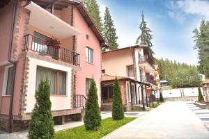 una casa rosa con árboles delante de ella en Ивелия Къща за гости, en Dospat