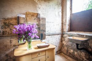 ein Badezimmer mit einem Waschbecken und einer Vase aus lila Blumen in der Unterkunft CAMP Agroturystyka Gorzelnia Gwieździn in Gwieździn