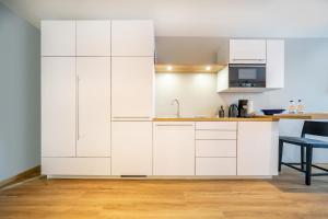 a kitchen with white cabinets and a table at bodenseezeit Apartmenthotel Garni in Lindau