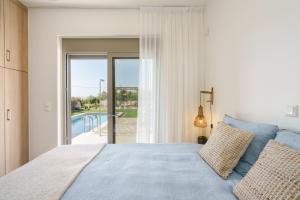 1 dormitorio con cama y vistas a la piscina en Modern Family Villa Leba with Private Pool & BBQ, en Agios Dimitrios