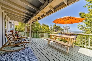 eine Holzterrasse mit einem Tisch, Stühlen und einem Sonnenschirm in der Unterkunft The River View House in Gold Beach