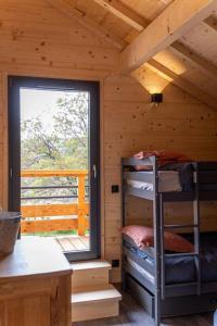 a wooden cabin with a bunk bed and a window at Chalet au coeur du Jura à 5min de la plage de Clairvaux 