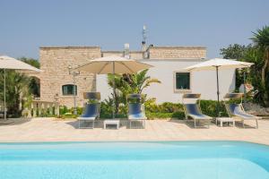 a pool with chairs and umbrellas and a house at B&B Tenuta Martinelli in Monopoli