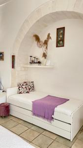 - une chambre avec un lit blanc et une couverture violette dans l'établissement Il Giardino dei Limoni, à Vieste